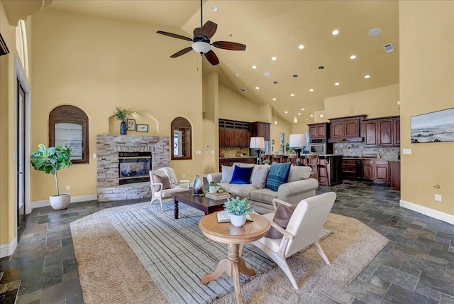 living room with a stone fireplace, high vaulted ceiling, and ceiling fan