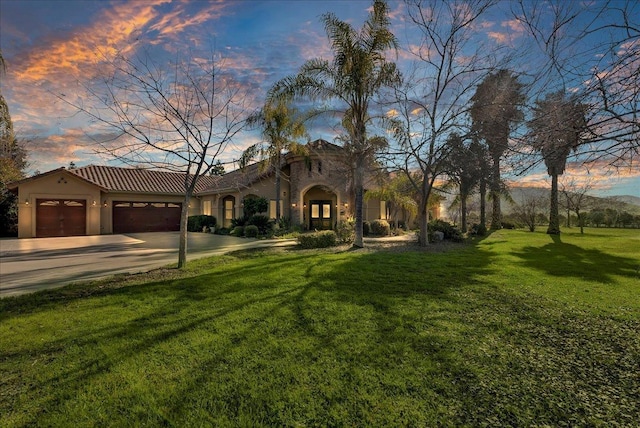 mediterranean / spanish-style home with a garage and a lawn