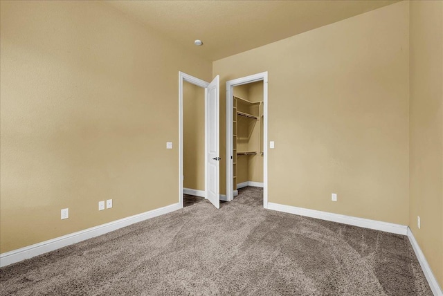 unfurnished bedroom with a spacious closet and carpet floors