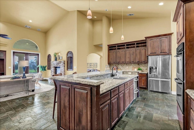 kitchen with high vaulted ceiling, tasteful backsplash, sink, hanging light fixtures, and stainless steel appliances