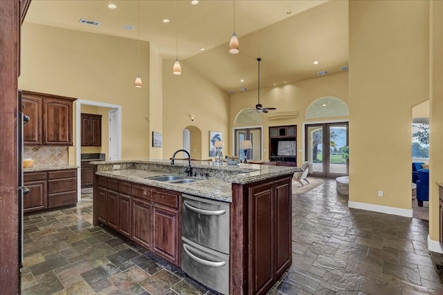 kitchen with a kitchen island with sink, sink, a towering ceiling, and pendant lighting