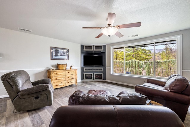 living room with hardwood / wood-style floors, a textured ceiling, and ceiling fan