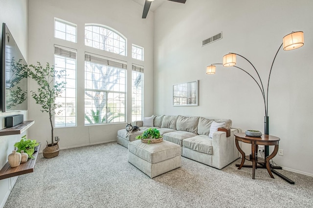 living room featuring ceiling fan, a towering ceiling, and carpet flooring