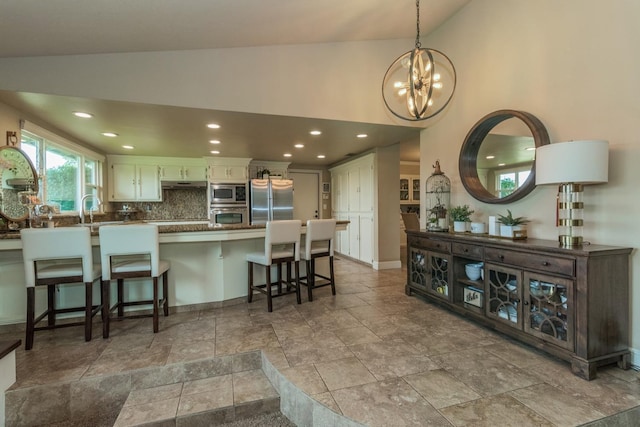 kitchen with white cabinetry, decorative backsplash, vaulted ceiling, and stainless steel appliances