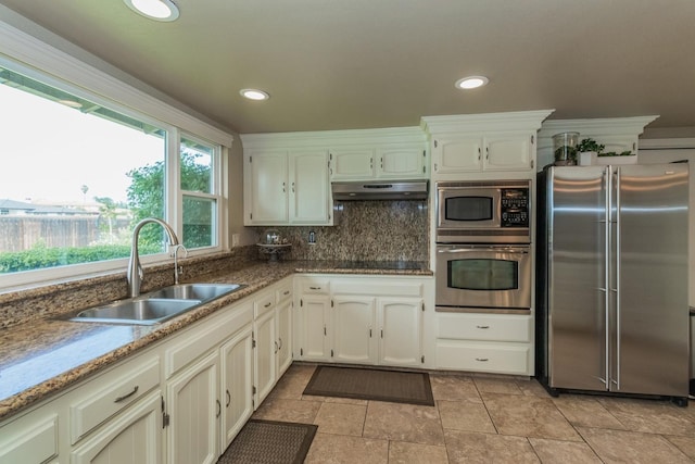 kitchen featuring tasteful backsplash, appliances with stainless steel finishes, sink, and dark stone countertops