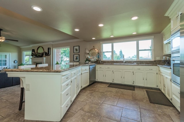 kitchen with dark stone countertops, white cabinetry, a kitchen breakfast bar, a healthy amount of sunlight, and kitchen peninsula