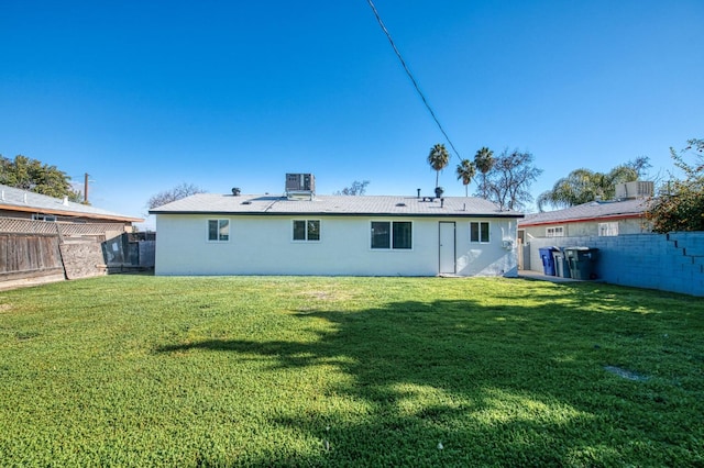 back of house featuring central AC unit and a lawn