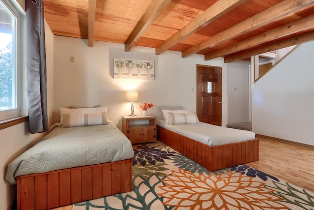 bedroom with beamed ceiling, wood ceiling, and light hardwood / wood-style flooring