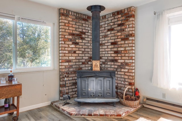 interior details featuring a baseboard radiator, wood-type flooring, and a wood stove