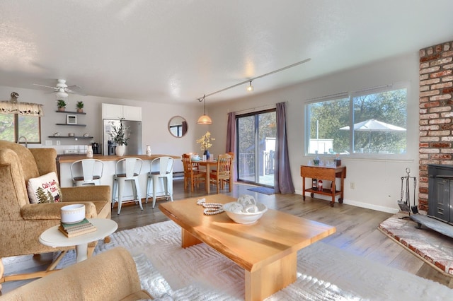 living room with ceiling fan, light hardwood / wood-style floors, and a textured ceiling