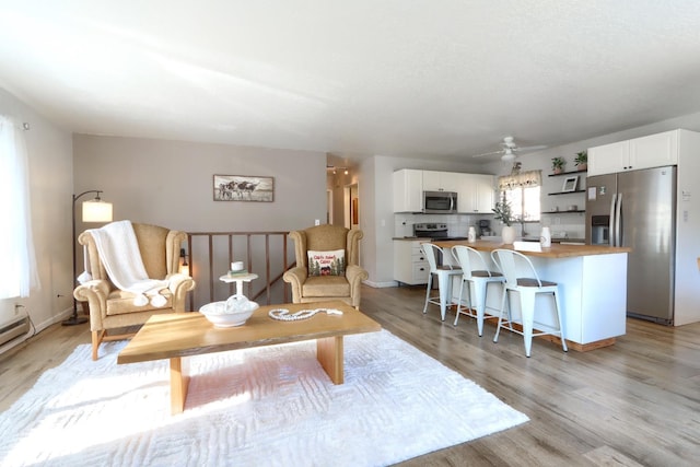 living room featuring ceiling fan, plenty of natural light, and light wood-type flooring