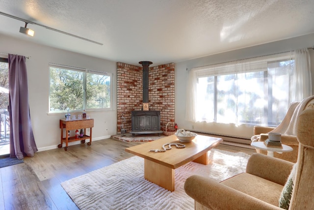 living room with a healthy amount of sunlight, wood-type flooring, a textured ceiling, and a wood stove