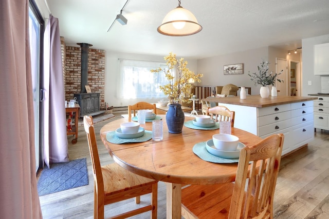 dining space featuring light hardwood / wood-style flooring, rail lighting, and a wood stove