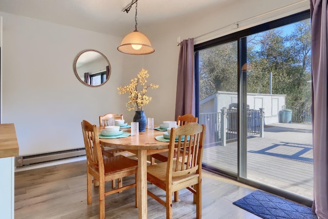 dining area with a baseboard heating unit and light wood-type flooring