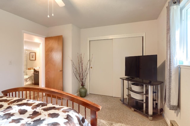 carpeted bedroom featuring ensuite bathroom, ceiling fan, and a closet