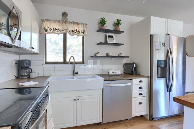 kitchen with sink, stainless steel appliances, light hardwood / wood-style floors, and white cabinets