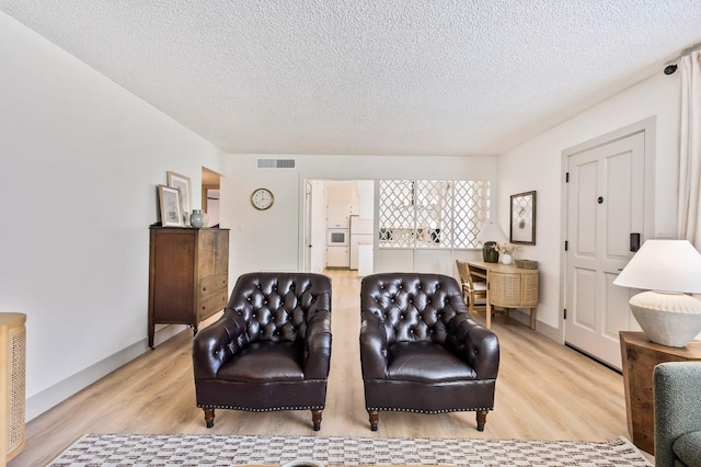 living room featuring light hardwood / wood-style flooring and a textured ceiling