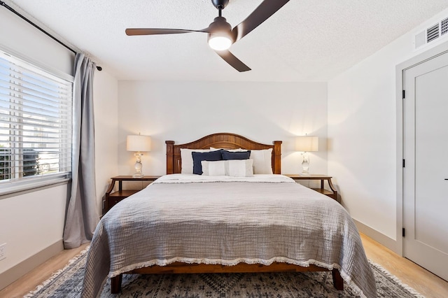 bedroom featuring a textured ceiling, ceiling fan, and light wood-type flooring