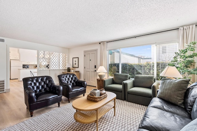 living room with light wood-type flooring and a textured ceiling