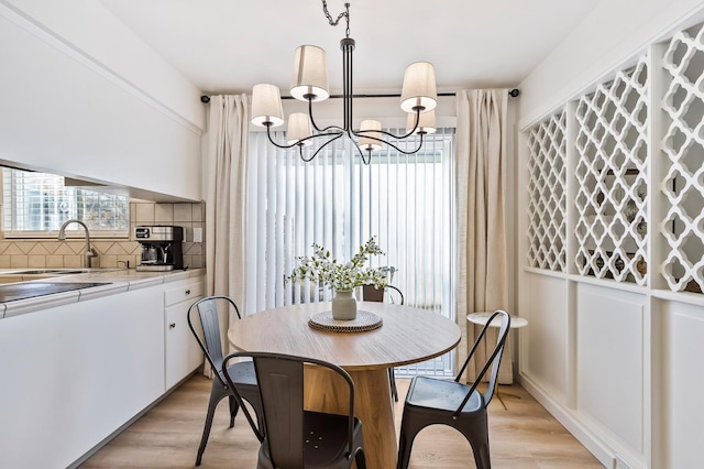 dining room featuring an inviting chandelier, sink, and light hardwood / wood-style floors