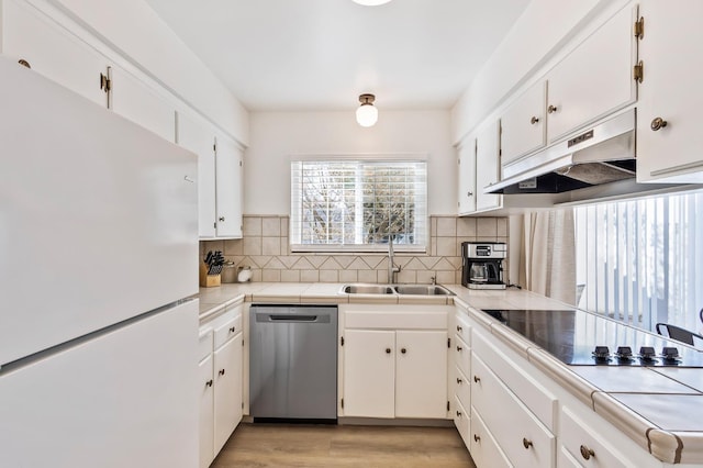 kitchen featuring sink, dishwasher, white cabinetry, decorative backsplash, and white fridge