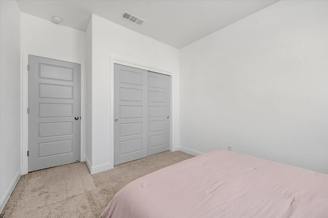 bedroom featuring light colored carpet and a closet