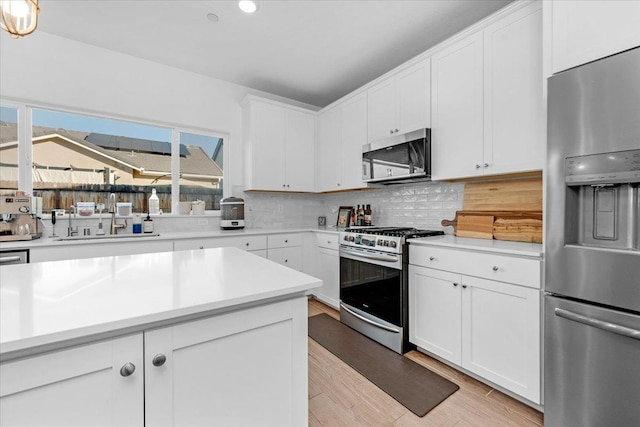 kitchen with tasteful backsplash, white cabinetry, and appliances with stainless steel finishes