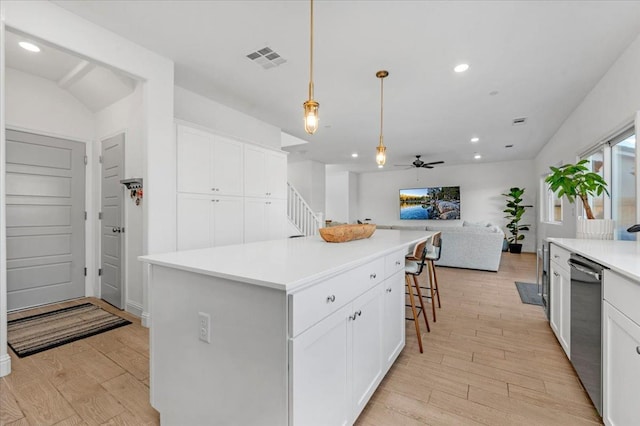 kitchen with dishwasher, hanging light fixtures, a center island, white cabinets, and a kitchen bar