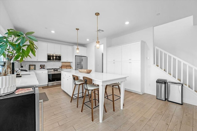 kitchen featuring pendant lighting, white cabinetry, and stainless steel appliances