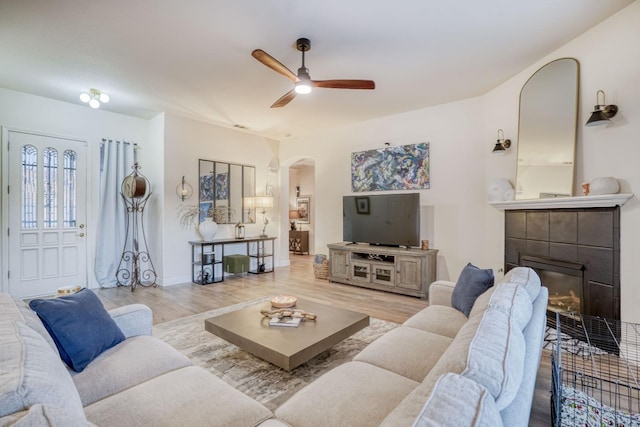 living room with ceiling fan, a fireplace, and light hardwood / wood-style floors