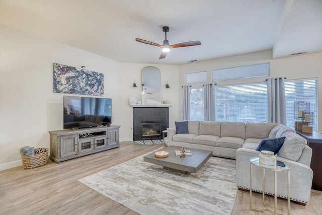 living room with ceiling fan, a fireplace, and light hardwood / wood-style floors