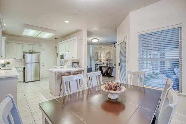 dining room featuring sink, light tile patterned floors, and ceiling fan