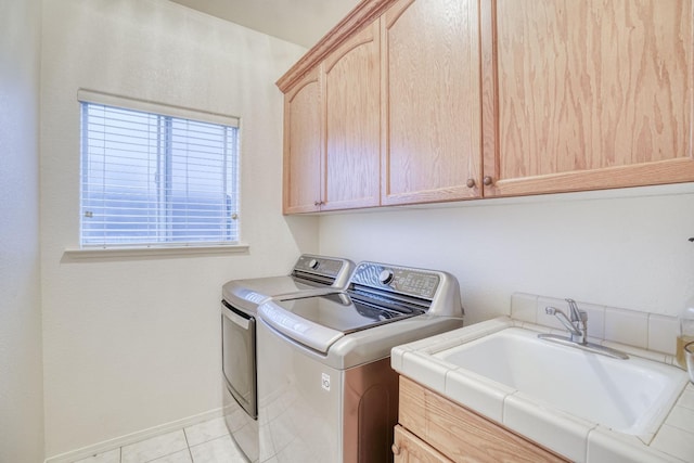 washroom featuring independent washer and dryer, sink, cabinets, and light tile patterned flooring