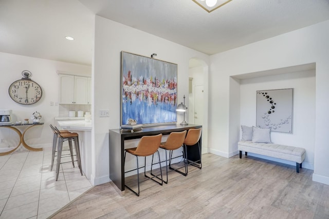 interior space with a breakfast bar, white cabinetry, backsplash, light hardwood / wood-style floors, and kitchen peninsula