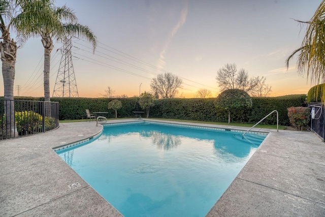 pool at dusk with a patio area