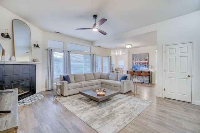 living room with ceiling fan, a fireplace, and light hardwood / wood-style floors