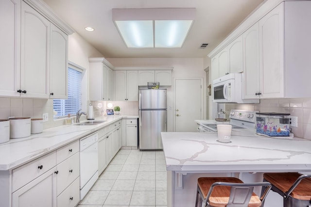 kitchen with white appliances, sink, and white cabinets