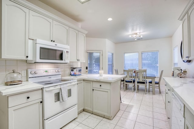 kitchen featuring light tile patterned flooring, kitchen peninsula, white appliances, decorative backsplash, and white cabinets