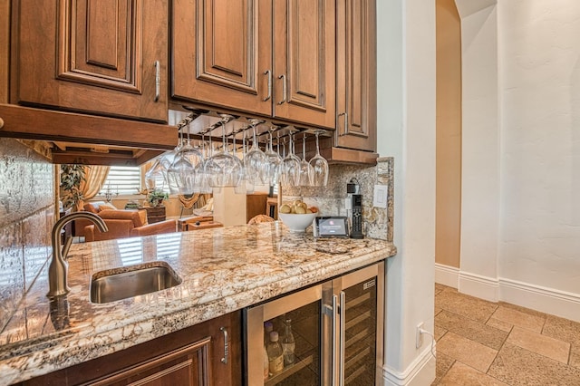 kitchen featuring wine cooler, sink, light stone counters, and tasteful backsplash