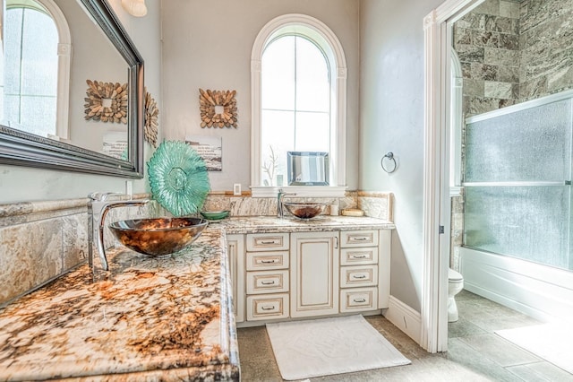 full bathroom with toilet, tile patterned floors, vanity, and shower / bath combination with glass door