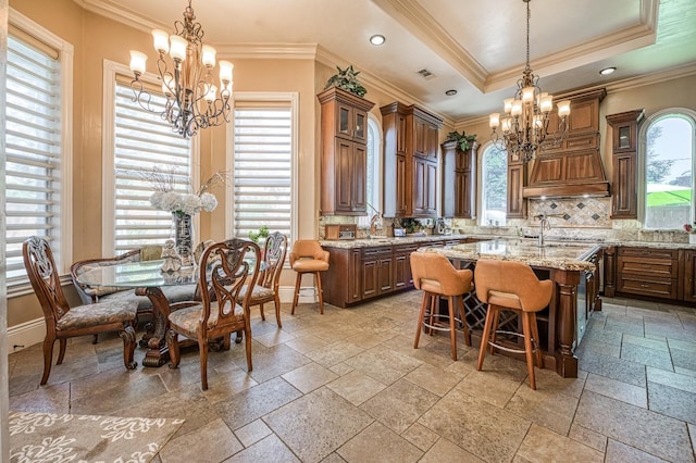 kitchen with a raised ceiling, a kitchen breakfast bar, and an inviting chandelier