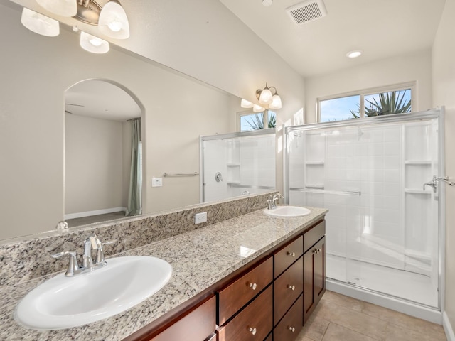 bathroom with a shower with door, vanity, and tile patterned flooring