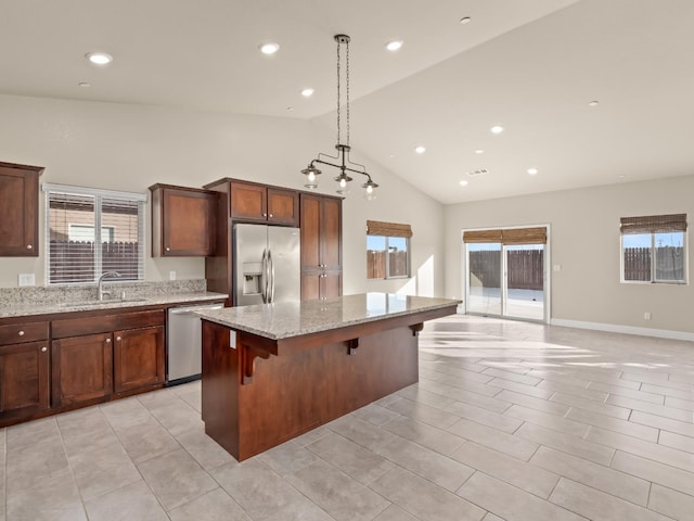 kitchen featuring sink, a breakfast bar area, a center island, stainless steel appliances, and light stone countertops