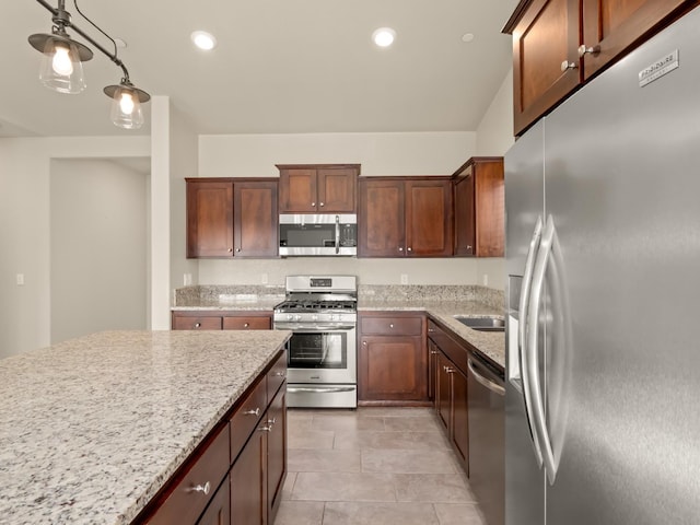 kitchen featuring light stone counters, decorative light fixtures, stainless steel appliances, and light tile patterned flooring