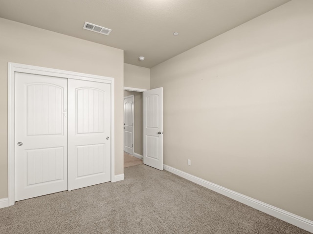 unfurnished bedroom with light colored carpet and a closet