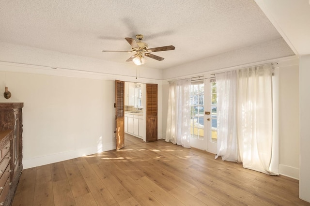 empty room featuring ceiling fan, sink, light hardwood / wood-style flooring, and a textured ceiling