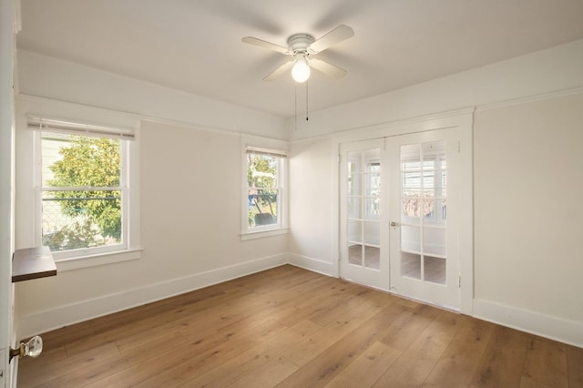 empty room featuring a wealth of natural light, ceiling fan, and light wood-type flooring