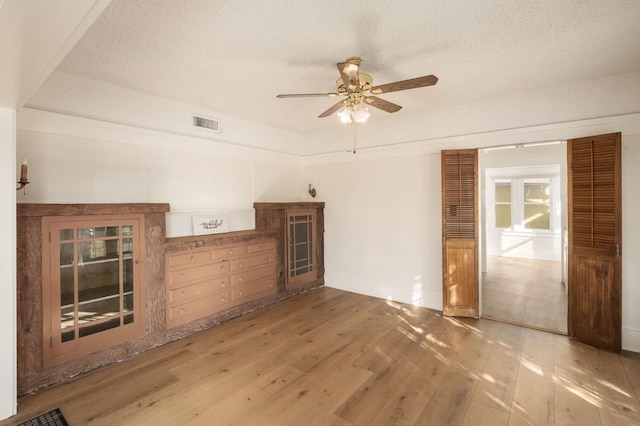 empty room with hardwood / wood-style floors, a textured ceiling, and ceiling fan