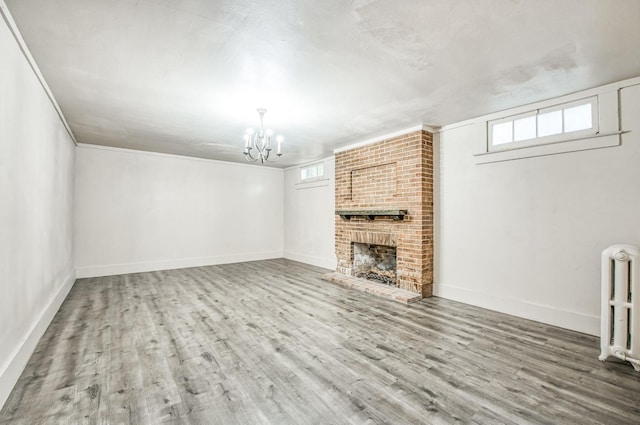 unfurnished living room with radiator heating unit, a wealth of natural light, a fireplace, and wood-type flooring