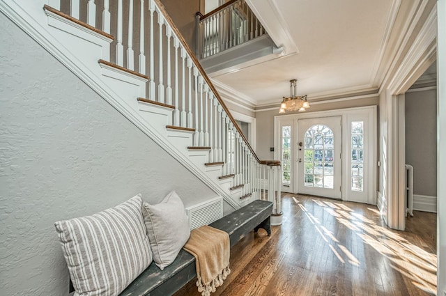 entrance foyer with crown molding, wood-type flooring, radiator heating unit, and a notable chandelier